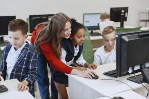 Educator helping students use computers in a classroom