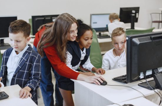 Educator helping students use computers in a classroom